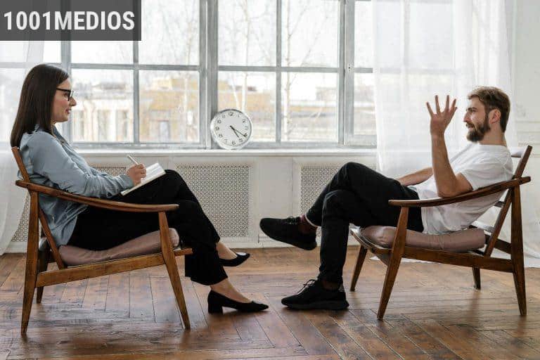 Person in Black Pants and Black Shoes Sitting on Brown Wooden Chair
