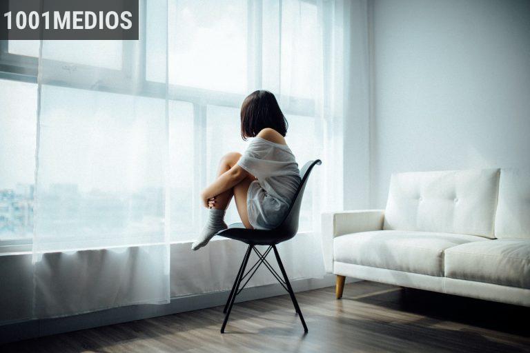 woman sitting on black chair in front of glass-panel window with white curtains