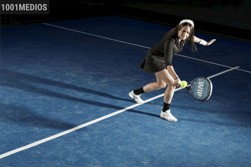 a young woman holding a tennis racquet on a tennis court