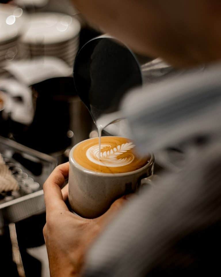 Barista sirviendo un café con latte art en una barra de café para eventos