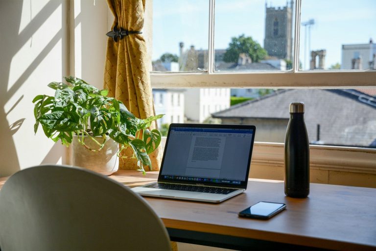 Portátil sobre una mesa de madera preparada como espacio de teletrabajo