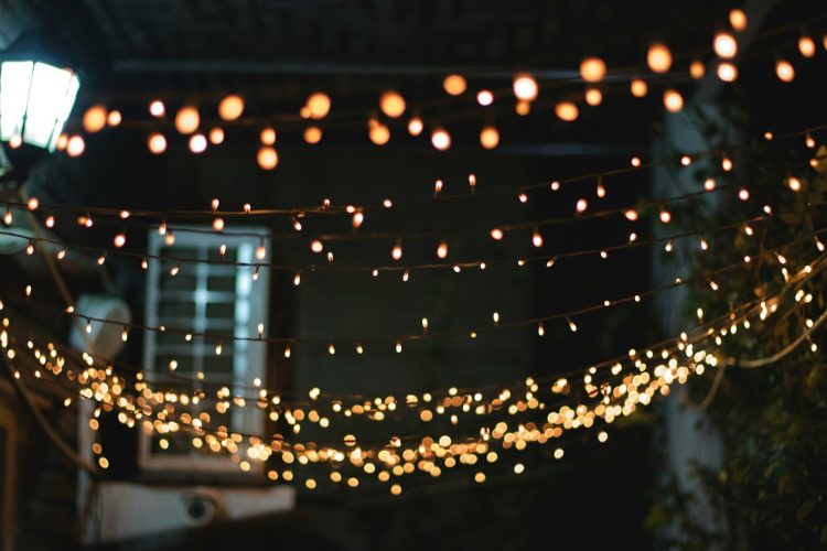 Guirnaldas de luces cálidas iluminando un jardín durante una fiesta nocturna