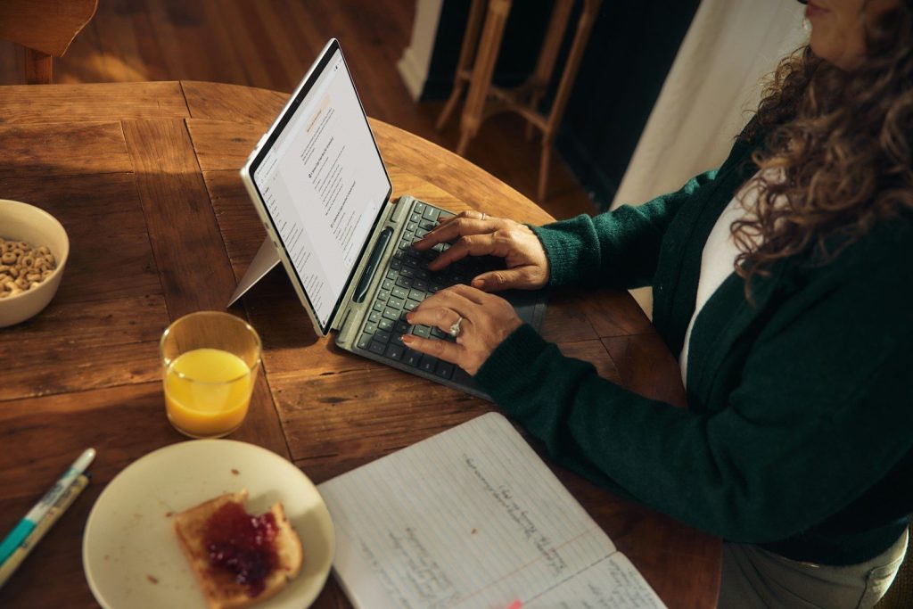 Mujer teletrabajando con el portátil en una mesa de madera de casa