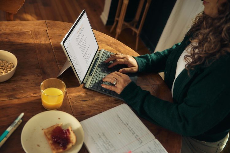 Mujer teletrabajando con el portátil en una mesa de madera de casa